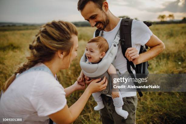 young family spending time outdoors - baby carrier stock pictures, royalty-free photos & images