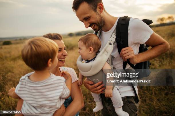family spending time outdoors - baby carrier stock pictures, royalty-free photos & images