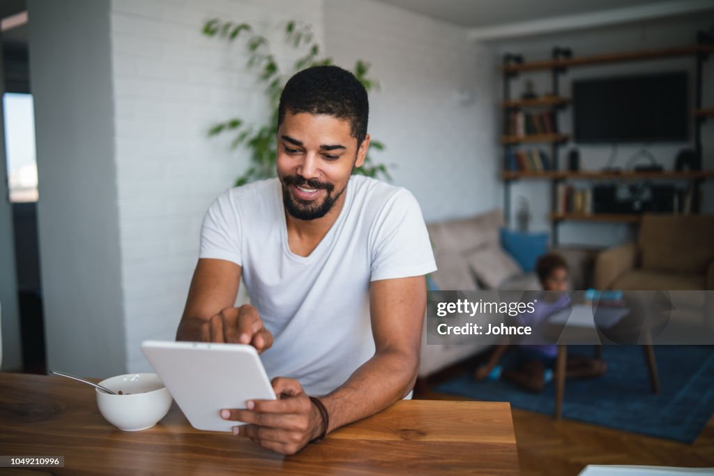 African man using tablet while having breakfast