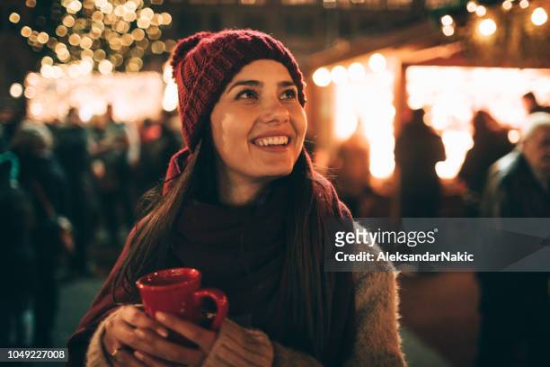 genieten van glühwein op kerstmarkt - christmas drinks stockfoto's en -beelden