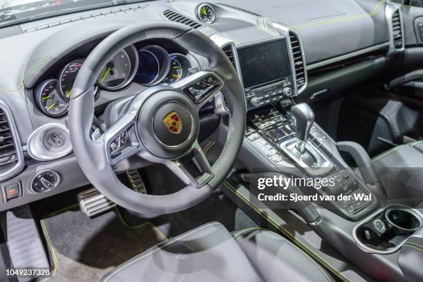 Interior on a Porsche Cayenne S E-Hybrid plug-in hybrid luxury SUV with black leather trim and information displays on the dashboard on display at...