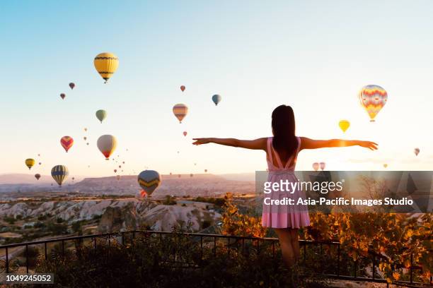 hübsche asiatin offenen armen beobachten bunten heißluftballons fliegen über das tal in kappadokien, türkei - hot middle eastern women stock-fotos und bilder