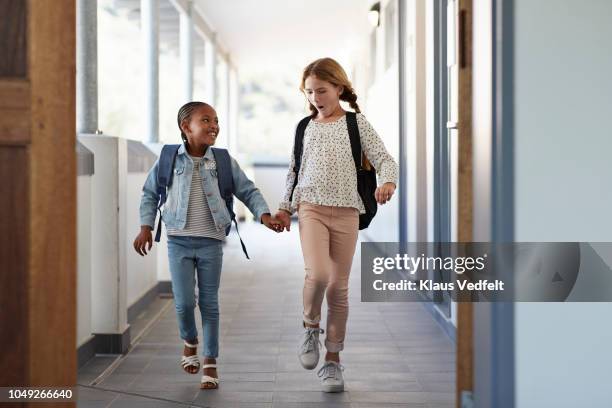 girlfriends walking hand in hand on school isle - kids modern school life stock-fotos und bilder