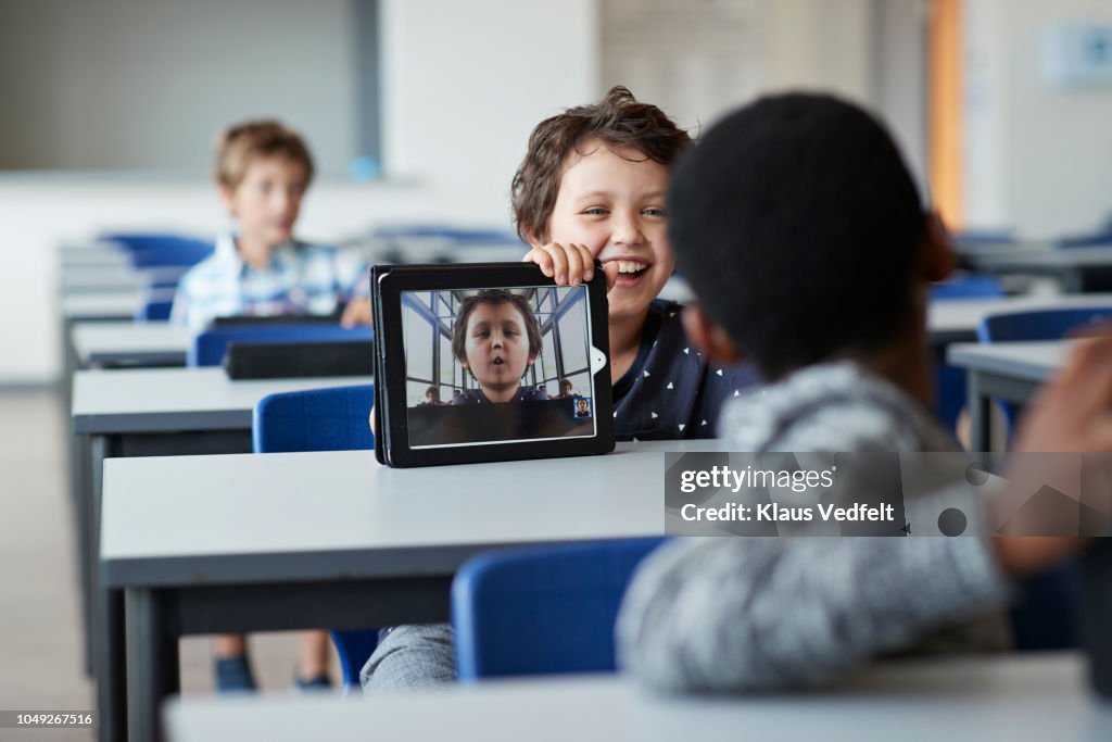 Laughing boy showing funny selfie to class mate