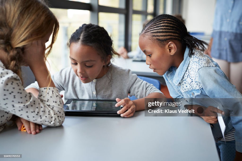 Girls looking at tablet together in classroom