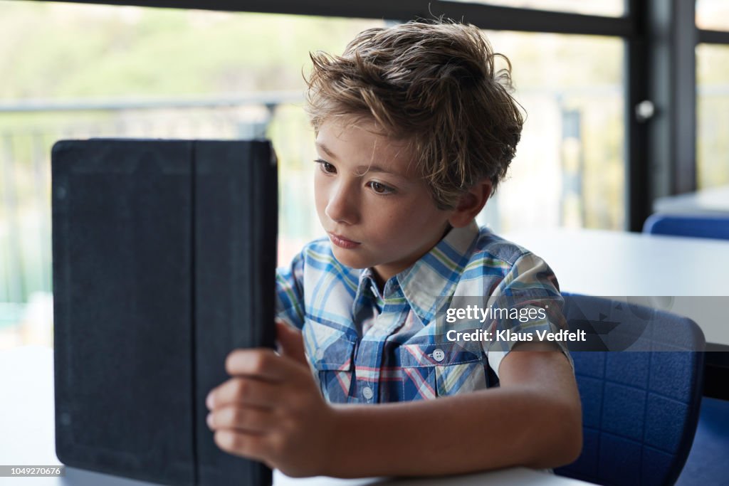 Boy reading on tablet in classroom