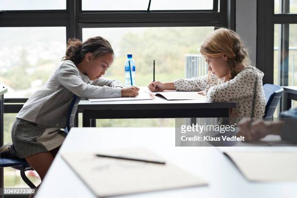 Girls writing in books in classroom