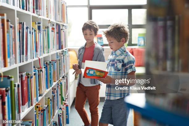 two brothers standing in school library - library kids stock pictures, royalty-free photos & images