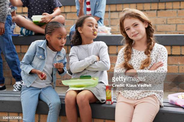 school children having lunch together outside the building - friend mischief stock-fotos und bilder