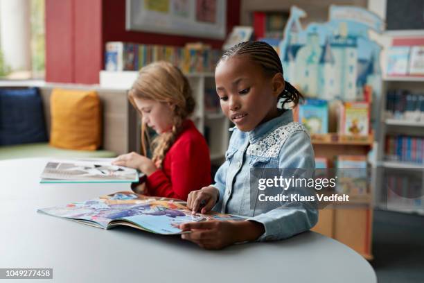 schoolgirls reading books in school library - kids read stockfoto's en -beelden