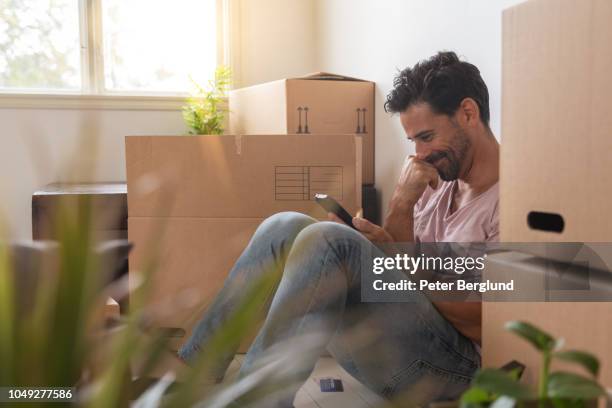 een man die verhuizen naar een nieuw huis - uitpakken activiteit stockfoto's en -beelden