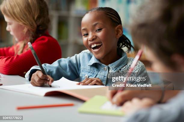 portrait of schoolgirl drawing at the school library and laughing - child learning stock pictures, royalty-free photos & images