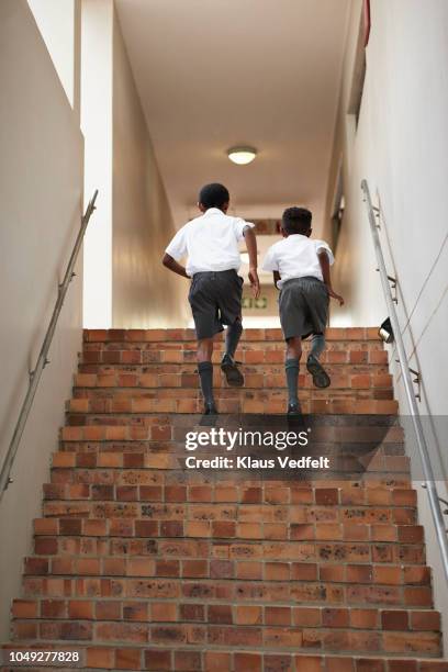 two school boys in uniforms running up staircase - carly simon signs copies of boys in the trees stockfoto's en -beelden