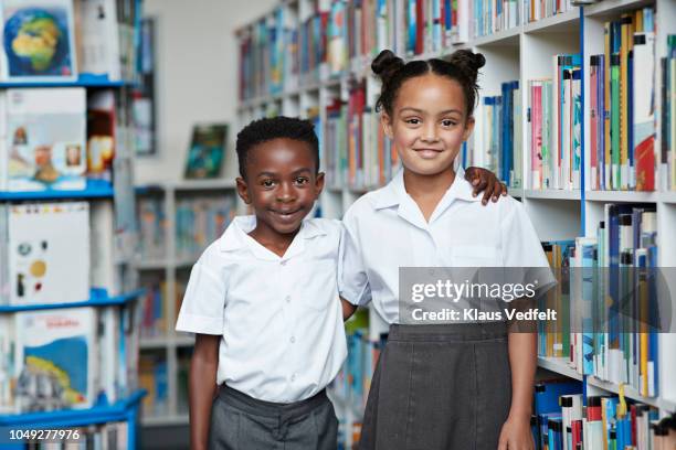 portrait of two cute school children at the library - private school uniform stock pictures, royalty-free photos & images