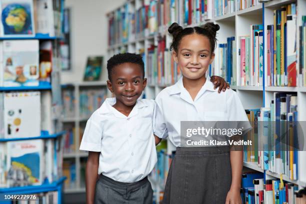 portrait of two cute school children at the library - uniform imagens e fotografias de stock