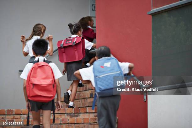 school children running on staircase to school building - terugkomen stockfoto's en -beelden