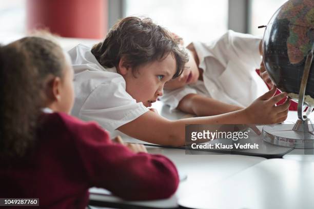 School children looking at globe in classroom
