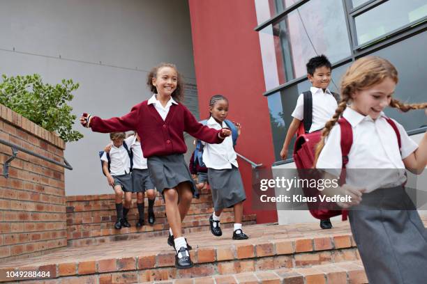 school children running and jumping off staircase from school building - private school uniform stock pictures, royalty-free photos & images