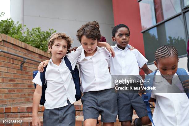 School children walking arm in arm on staircase to school building