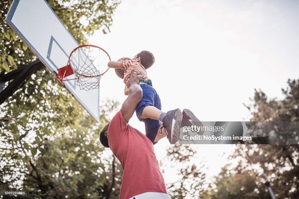 Vater und Sohn Spaß haben, spielen Basketball im freien