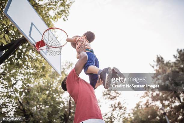 father and son having fun, playing basketball outdoors - taking a shot sport stock pictures, royalty-free photos & images