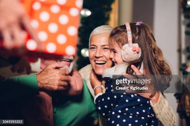 senior couple hugging grandchildren - hug christmas stock pictures, royalty-free photos & images