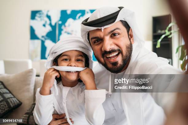arabische mann unter einem selfie mit seinem sohn auf dem sofa zu hause - two young arabic children only indoor portrait stock-fotos und bilder