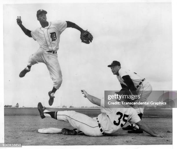 American baseball player Jake Wood , of the Detroit Tigers team, jumps up to throw a ball as his teammate Steve Boros slides into the base, watched...