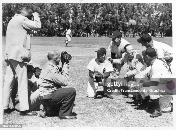 Photographers take pictures of American baseball executive Larry MacPhail as he poses with a group of unidentified New York Yankees rookies during...