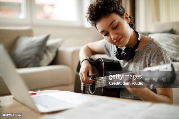 niña sonriente tocando una guitarra en casa - instrumentos musicales fotografías e imágenes de stock