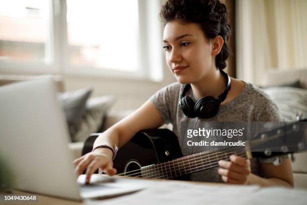 smiling girl playing a guitar at home - songwriter stock pictures, royalty-free photos & images