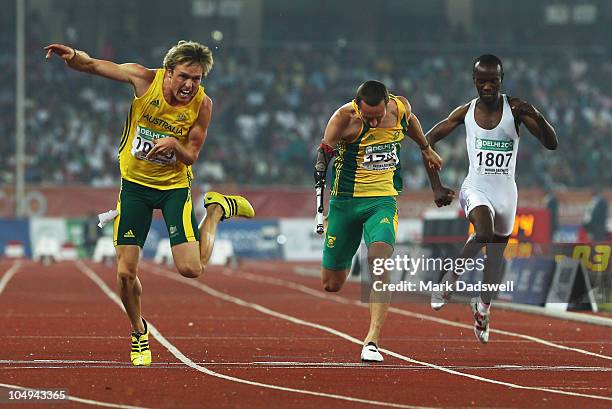 Simon Patmore of Australia crosses the line to win gold in the men's T46 100 metres final next to David Roos of South Africa and Herman Muvunyi of...