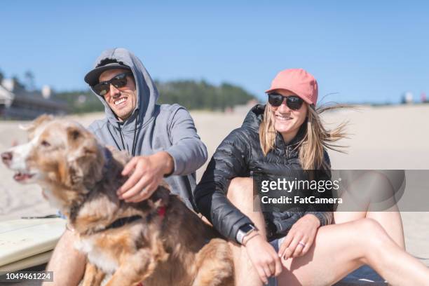 una joven pareja relajante en la playa con su perro - tillamook county fotografías e imágenes de stock