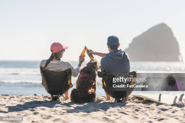 a young couple relaxing on the beach with their dog - oregon coast stock pictures, royalty-free photos & images