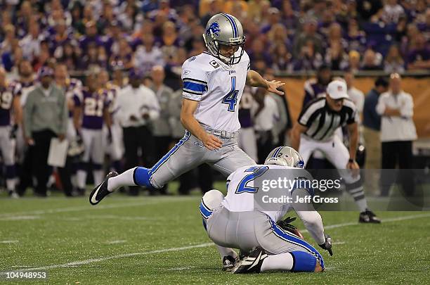 Kicker Jason Hanson of the Detroit Lions kicks as place kicker Nick Harris holds against the Minnesota Vikings at Mall of America Field on September...