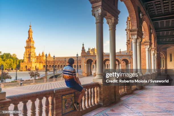 tourist admiring plaza de espana from portico, seville - seville spain stock pictures, royalty-free photos & images