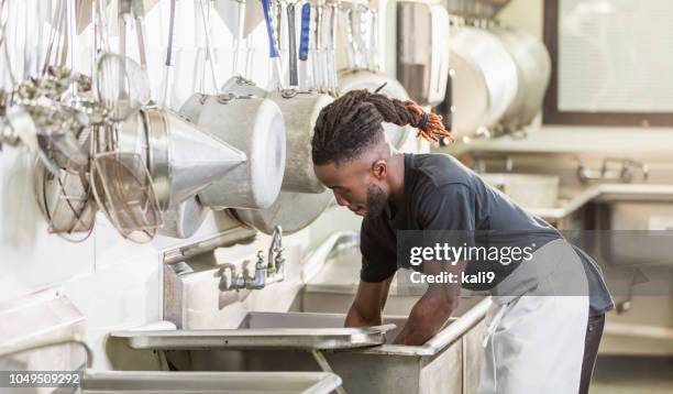 young african-american man working in commercial kitchen - restaurant cleaning stock pictures, royalty-free photos & images