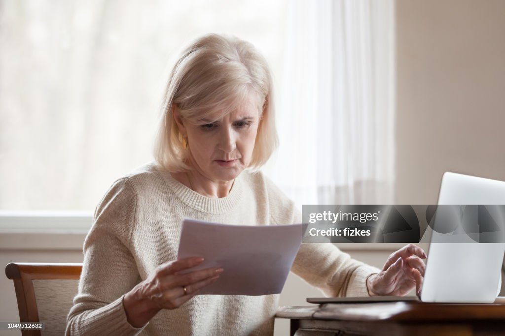 Serious frustrated middle aged woman troubled with domestic bills