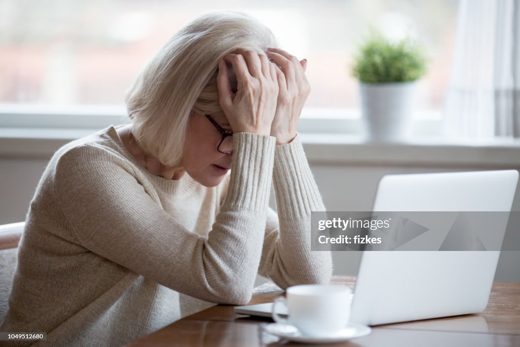 Middle-aged woman in front of laptop frustrated by bad news