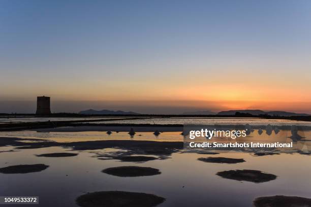 scenic sunset with medieval salt manufacturing tower and traditional salt pans and flats in trapani, sicily, italy - marsala stock pictures, royalty-free photos & images