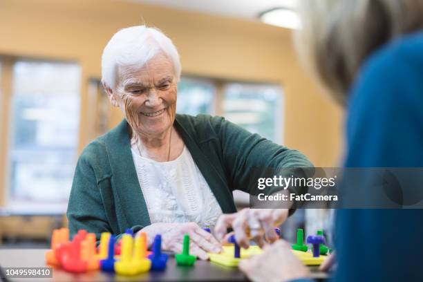 occupational therapist works with an elderly woman - speech therapy imagens e fotografias de stock