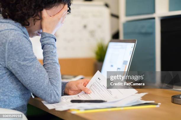 une jeune femme travaillant sur ses impôts - impôt sur le revenu photos et images de collection