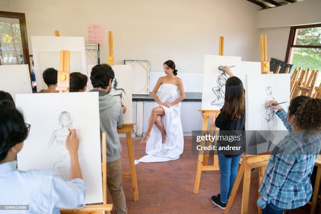 Group of people painting a live model in an art class