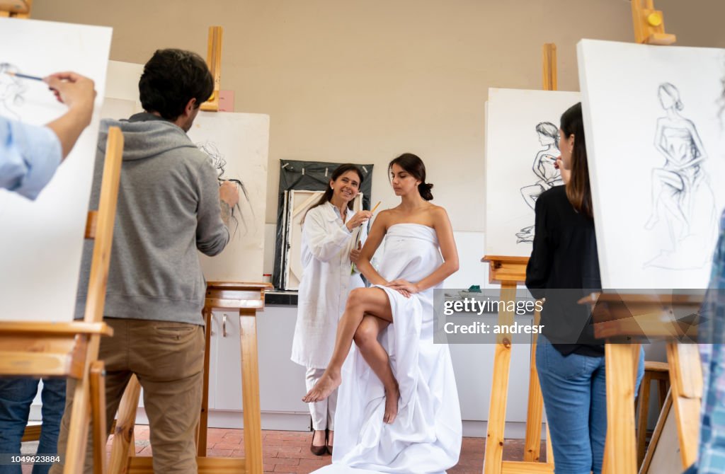 Group of people painting a live model in an art class