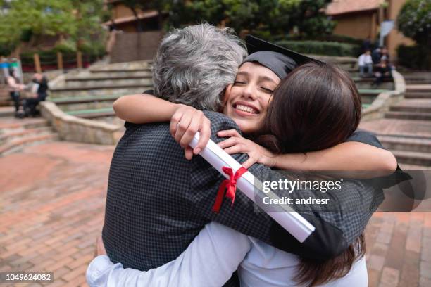 proud parents hugging their daughter and celebrating her graduation - son graduation stock pictures, royalty-free photos & images