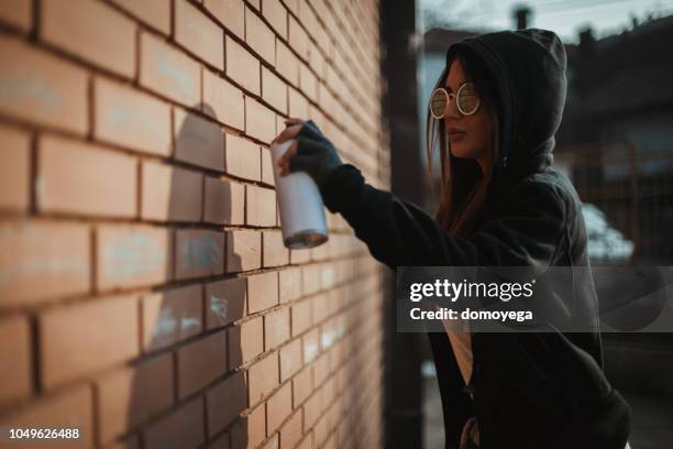 woman wearing hooded shirt and drawing graffiti on the wall - free hand sketch street stock pictures, royalty-free photos & images