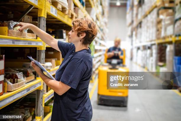 woman checking packages on warehouse racks - arranging products stock pictures, royalty-free photos & images