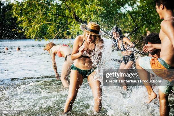 girl being splashed by friend while playing in lake - group of beautiful people stock pictures, royalty-free photos & images