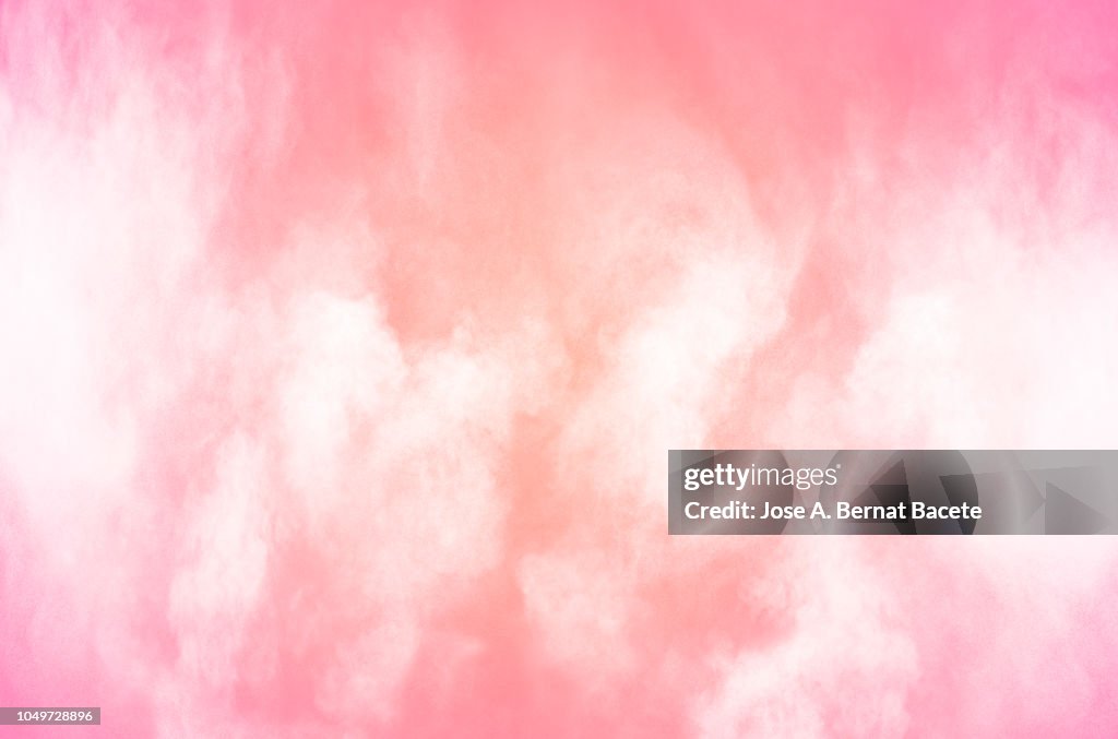 Explosion by an impact of a cloud of particles of powder of color white on a light pink background.