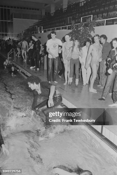 Irish musician and songwriter Phil Lynott of Thin Lizzy thrown inside a pool during a party, UK, 26th October 1979.